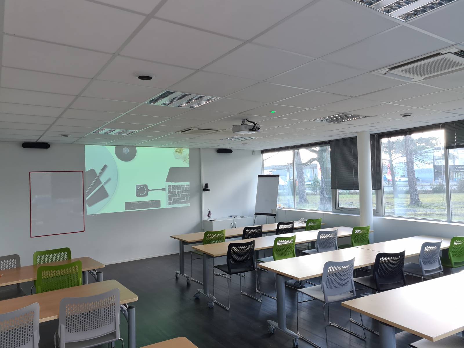 Salle de formation moderne à Bordeaux équipée d’un vidéoprojecteur, de micros plafond et d’un système sans fil ClickShare.