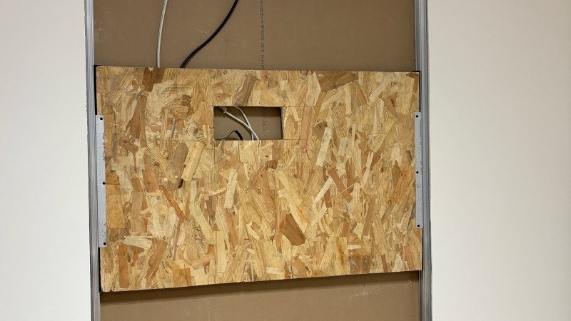 Renfort de cloison avec bois et équerres métalliques pour assurer la fixation sécurisée d’un écran